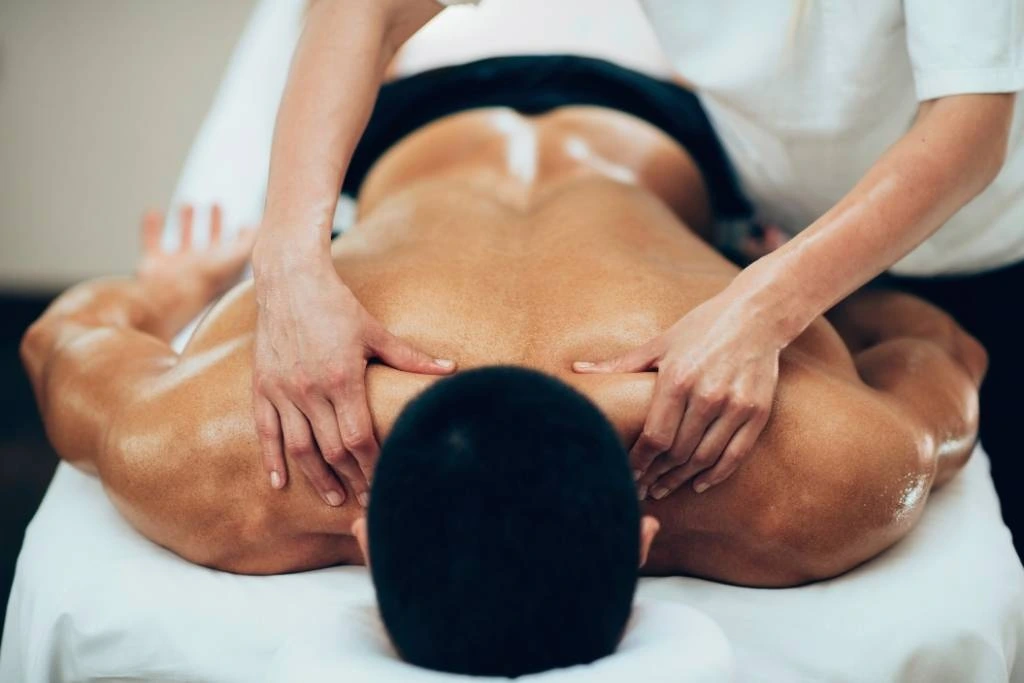 A close-up of a deep tissue massage in progress at Serenity Head Spa, showing hands working on muscle knots in the back. This differs from Swedish massage, which is typically more superficial.
