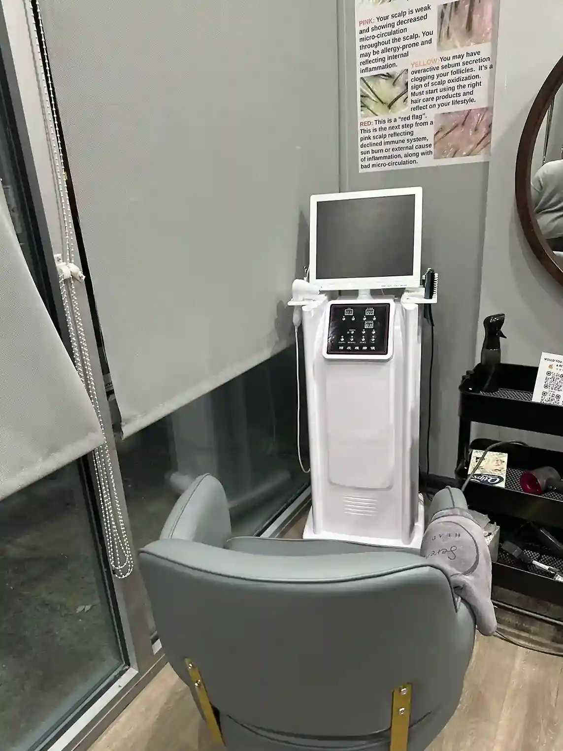 A hair and scalp analysis station with a reclining chair, a specialized machine, and a poster explaining scalp conditions.