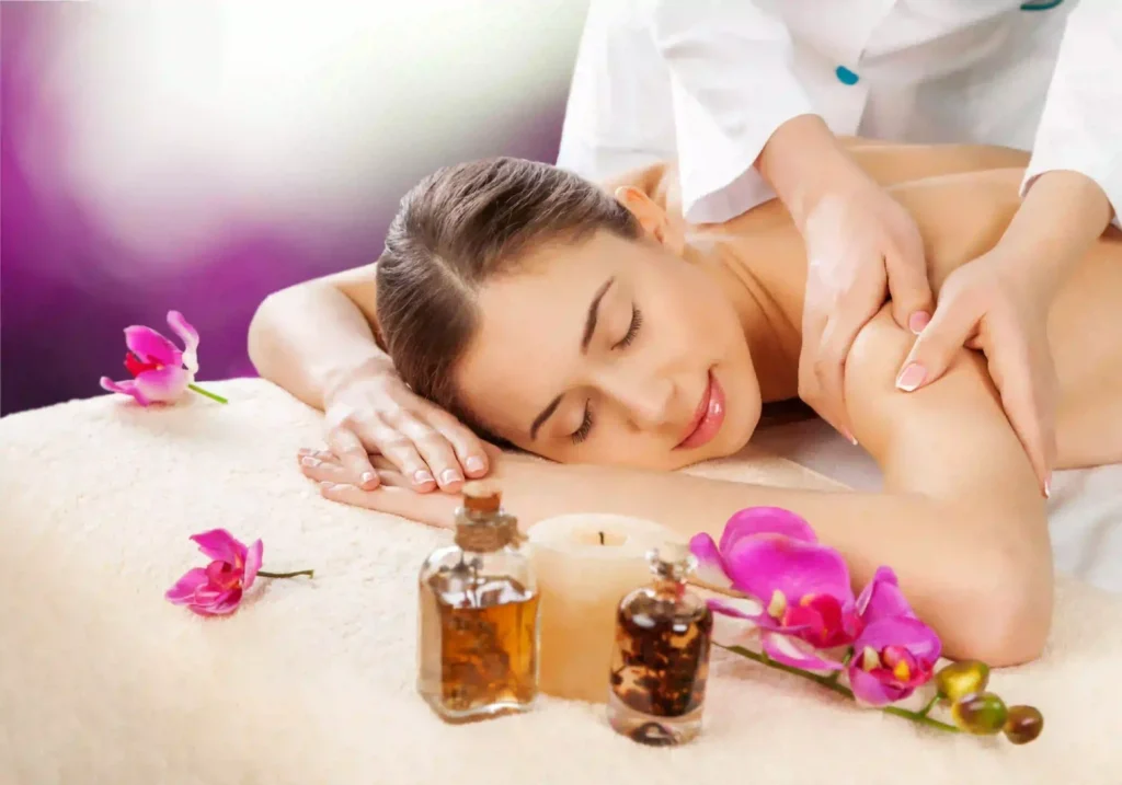 : A Woman Receiving A Professional Full Body Massage At A Spa, Featuring Essential Oils, A Lit Candle, And Pink Orchids On A Massage Table.