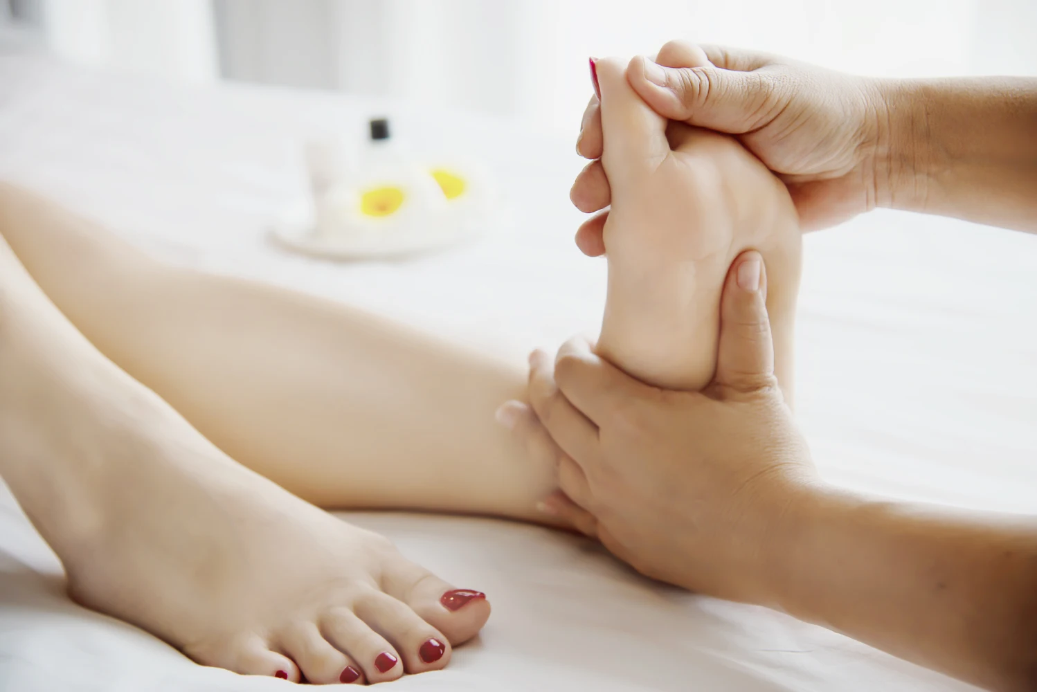 Close-Up Of A Therapist Performing A Relaxing Foot Massage On A Client In A Bright Spa Setting.