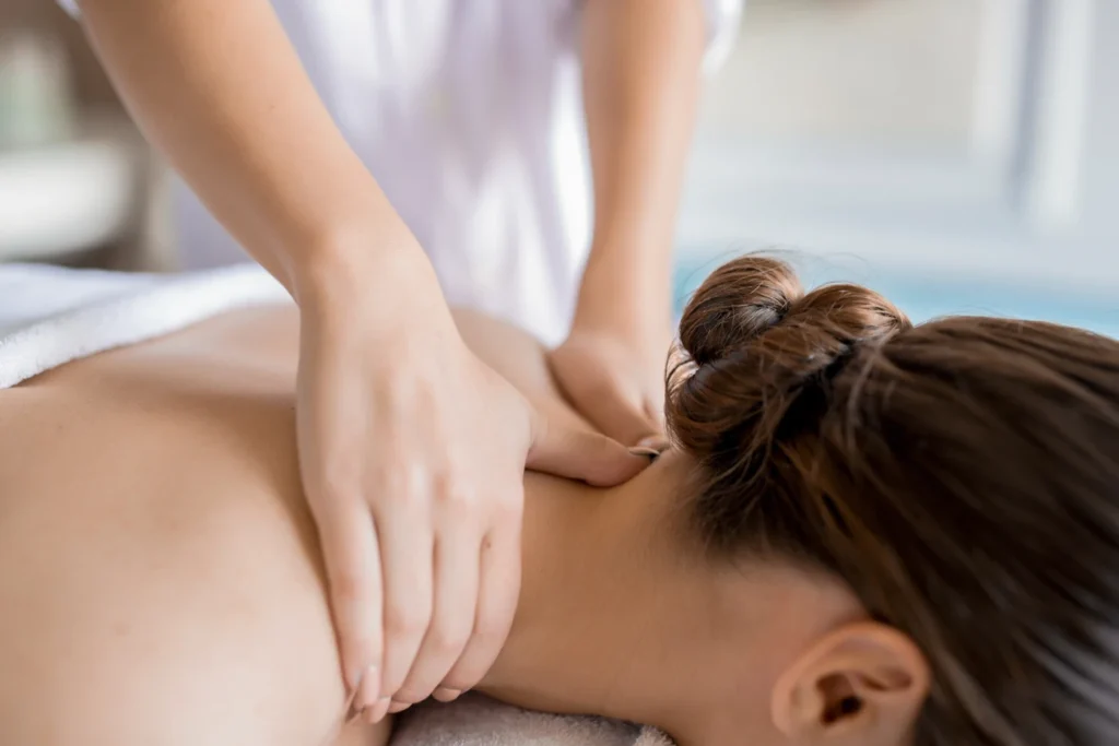 A Close-Up View Of A Massage Therapist Applying Pressure To A Woman'S Neck And Shoulders During A Therapeutic Spa Session.