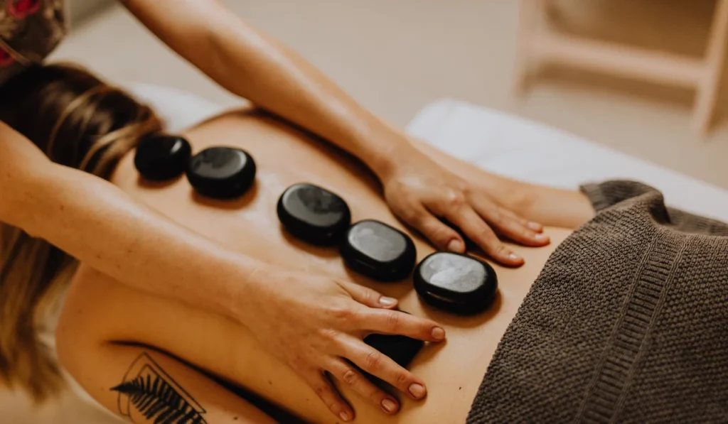Massage For Stress Relief: A Simple Guide To Calming Your Mind And Body 3 Close-Up Of A Client Receiving A Professional Hot Stone Therapy Session At A Wellness Spa To Relieve Muscle Tension And Stress.
